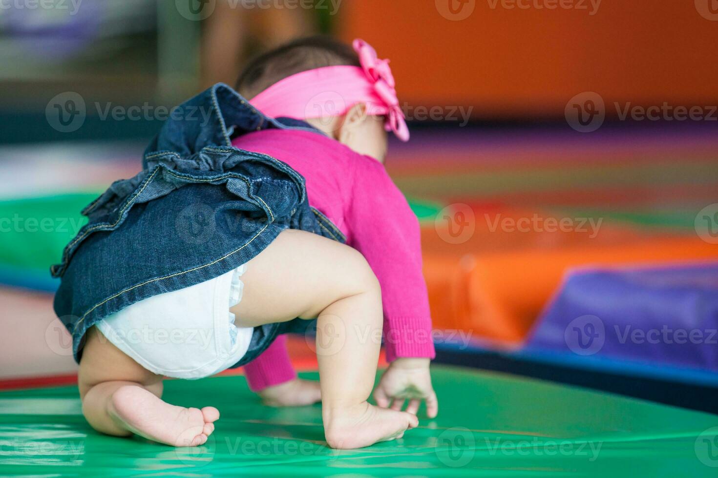 hermosa diez meses bebé niña gateando en un vistoso antecedentes. temprano estímulo para niños pequeños concepto. foto