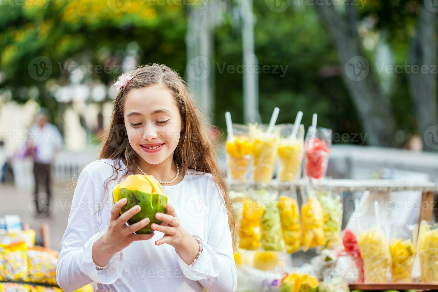 hermosa joven niña a paseo bolívar cuadrado en el ciudad de cali comiendo tropical frutas en Colombia foto