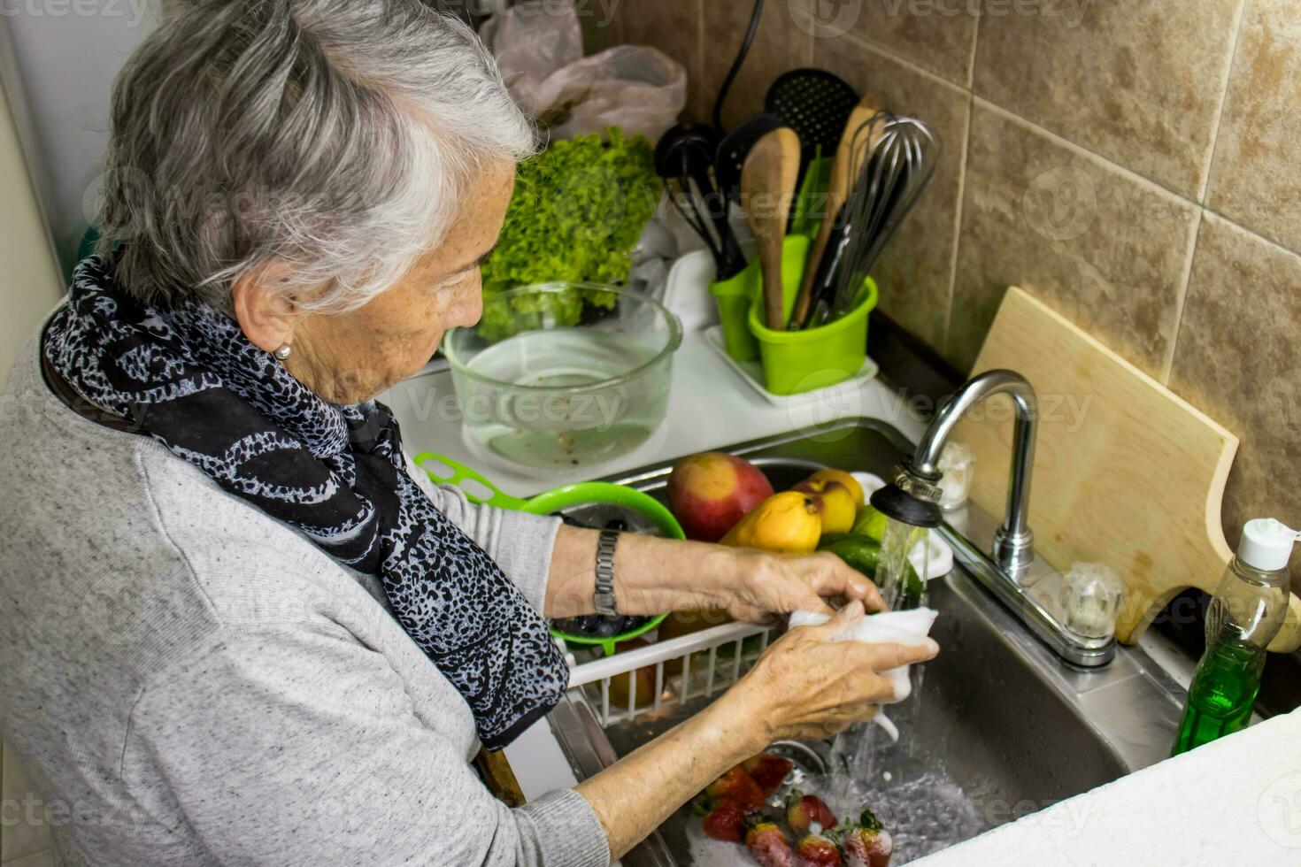 mayor mujer a hogar Lavado y desinfectar frutas y vegetales. foto