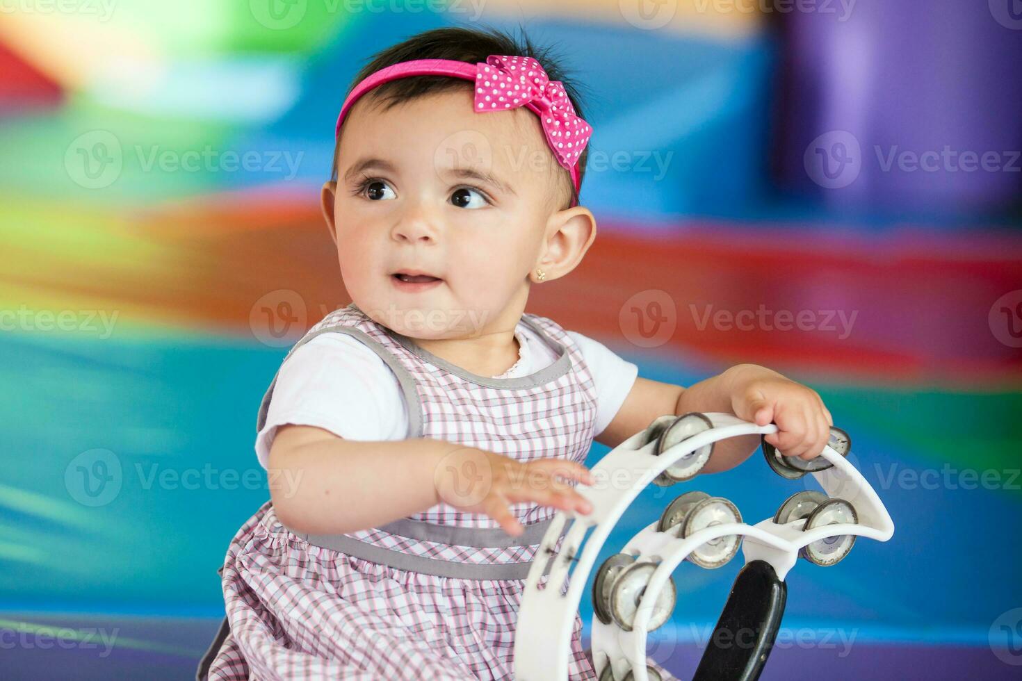 hermosa diez meses bebé niña jugando con un pandereta. temprano estímulo para niños pequeños concepto. foto