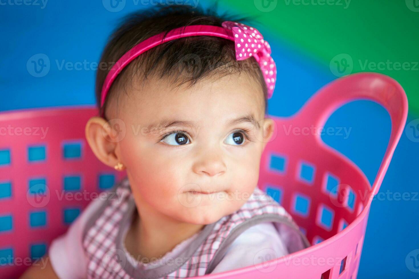 Beautiful ten months baby girl playing in a pink basket. Early stimulation for toddlers concept. photo