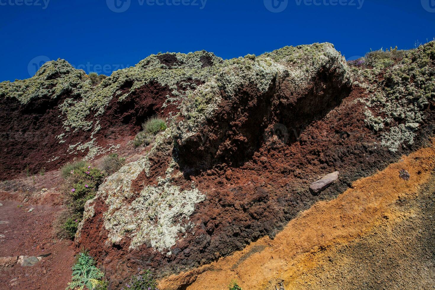 Red, orange and black stratified cliffs in Santorini Island photo