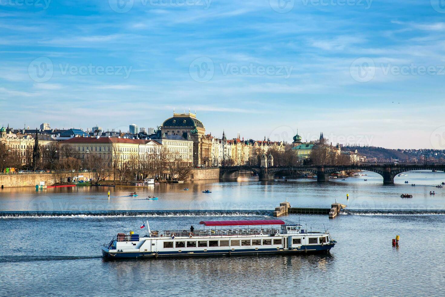Boat navigating on Vlava river at sunset in Prague photo