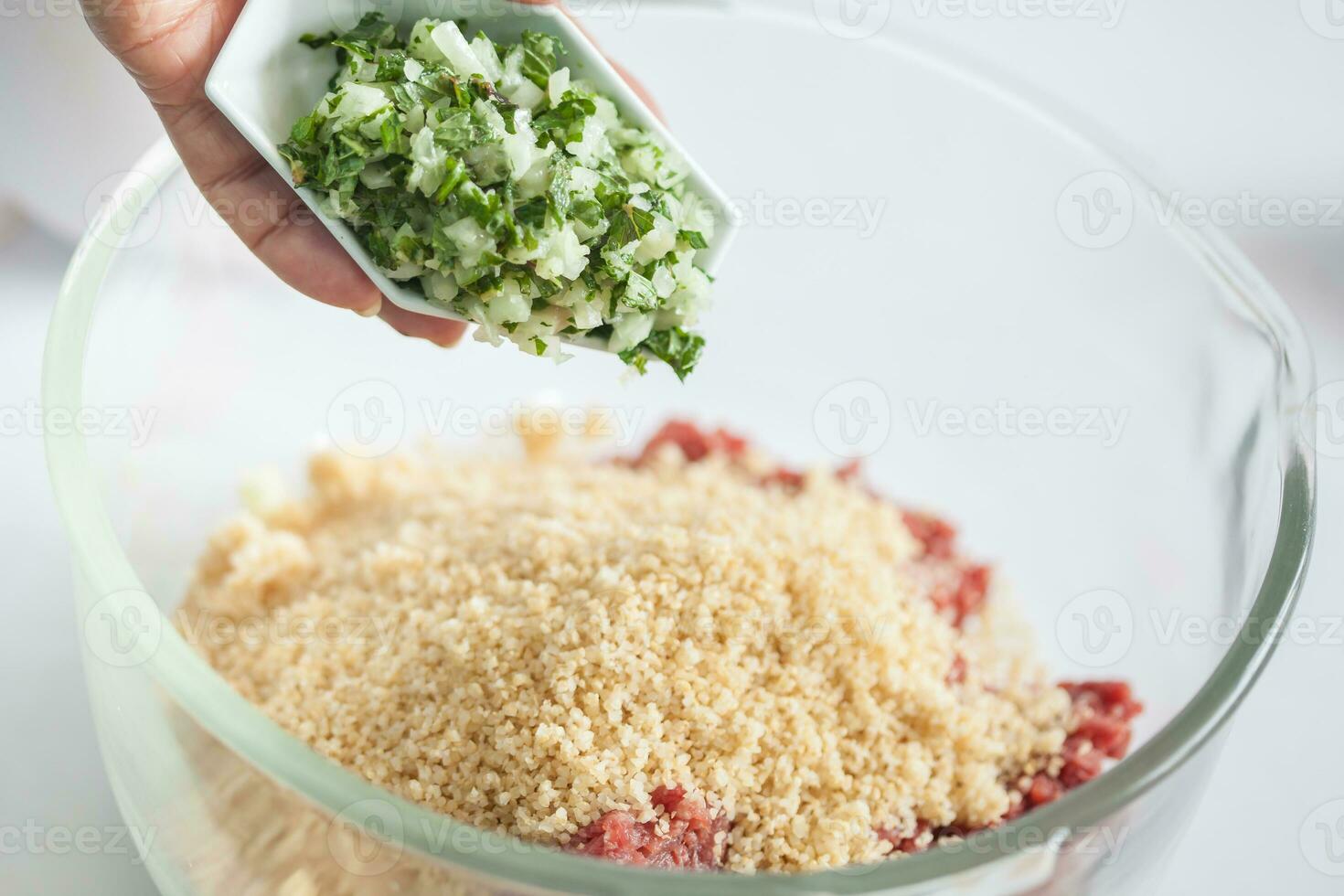 Step by step Levantine cuisine kibbeh preparation. Adding the ingredients to prepare kibbeh into a bowl photo