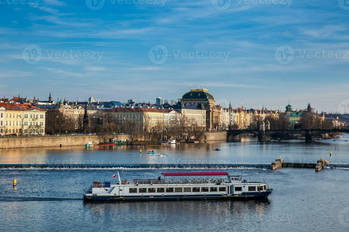 Boat navigating on Vlava river at sunset in Prague photo