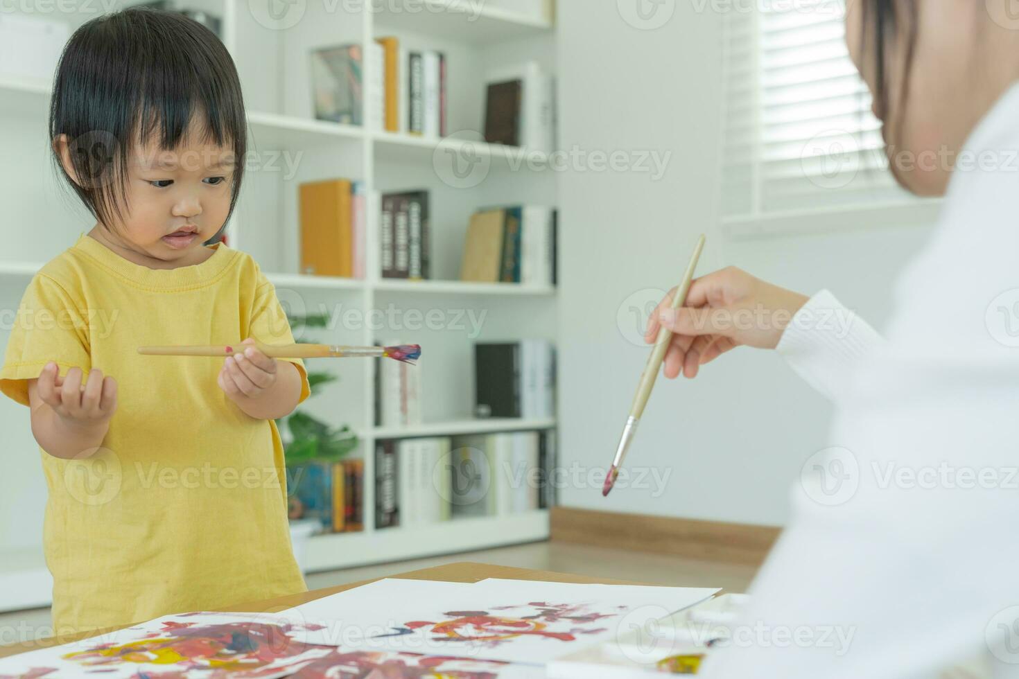 contento Asia madre jugando aprendizaje pintar para pequeño muchacha. gracioso familia es contento y emocionado en el casa. madre y hija teniendo divertido gasto hora juntos. día festivo, actividad foto