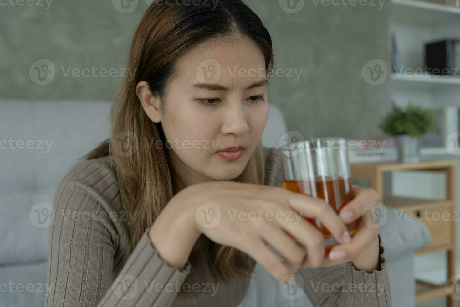 Depressed young Asian woman addicted feeling bad drinking whiskey alone at home, stressed frustrated lonely drinking alcohol suffers from problematic liquor, alcoholism, life and family problems photo