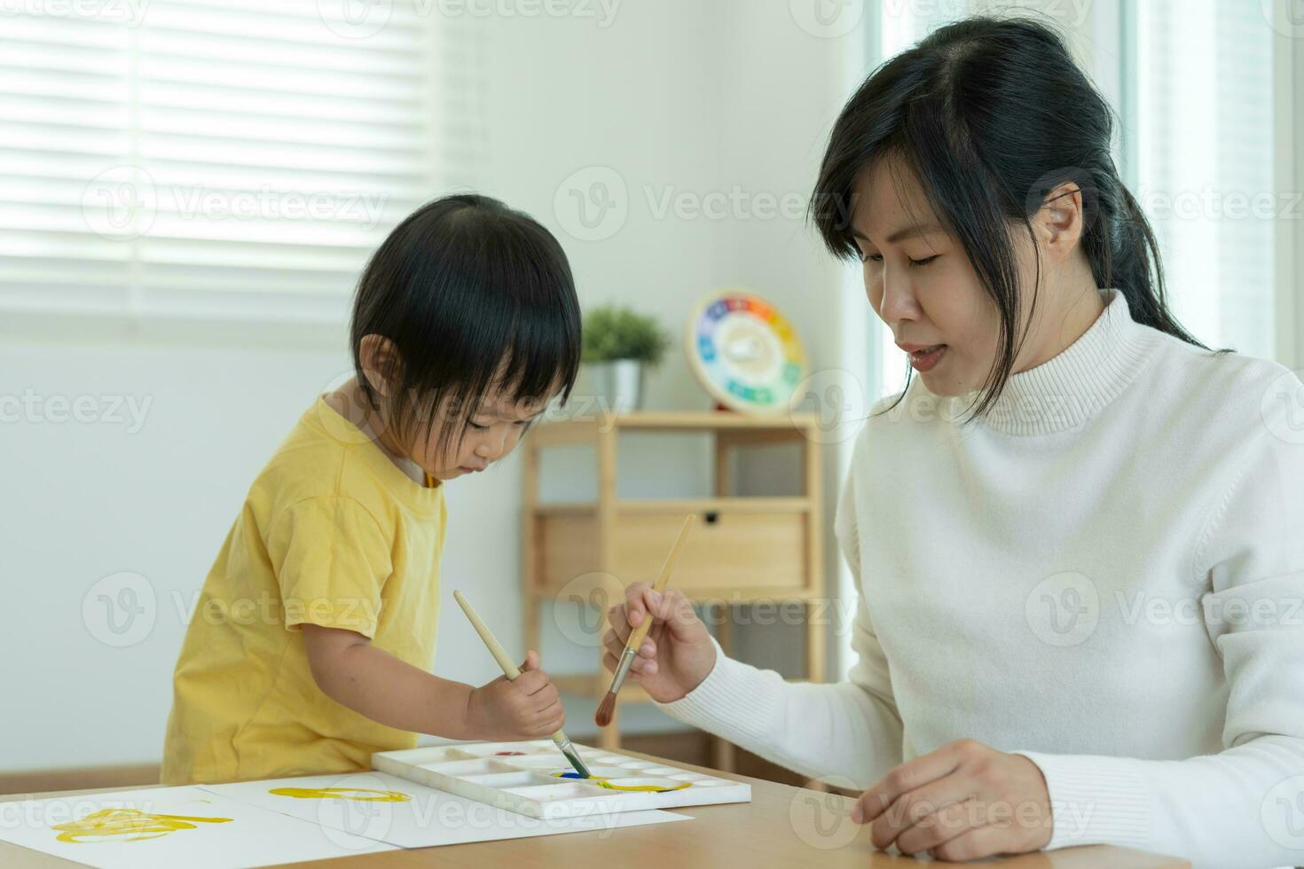 contento Asia madre jugando aprendizaje pintar para pequeño muchacha. gracioso familia es contento y emocionado en el casa. madre y hija teniendo divertido gasto hora juntos. día festivo, actividad foto