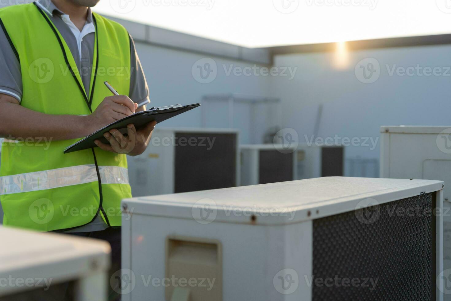 Asian maintenance engineer works on the roof of factory. contractor inspect compressor system and plans installation of air condition systems in construction. Checklist, inspector, control photo