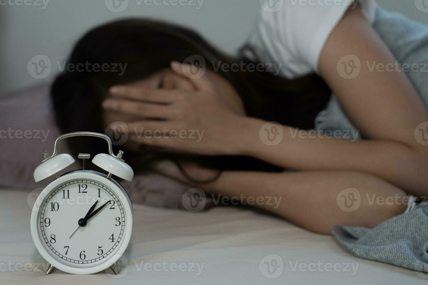 asian woman in bed late trying to sleep suffering insomnia, sleepless or scared in a nightmare, looking sad worried and stressed. Tired and headache or migraine waking up in the middle of the night. photo