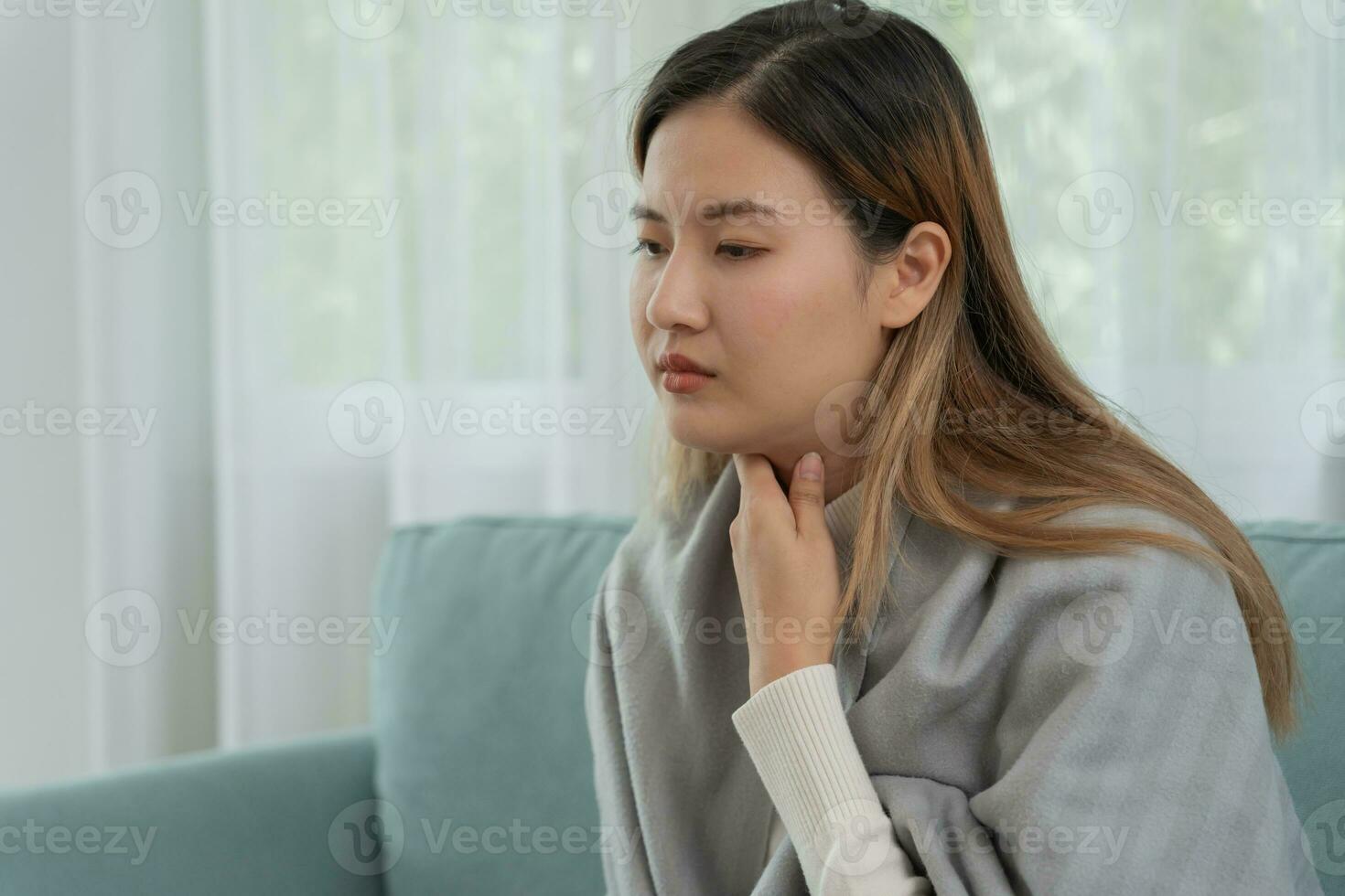 aisa mujer poner su mano en su cuello debido a un dolorido garganta. hembra amigdalitis causas un inflamación. tratado por tomando agua, tomando antibióticos, consultar un doctor, virus, corona virus, influenza, gripe foto