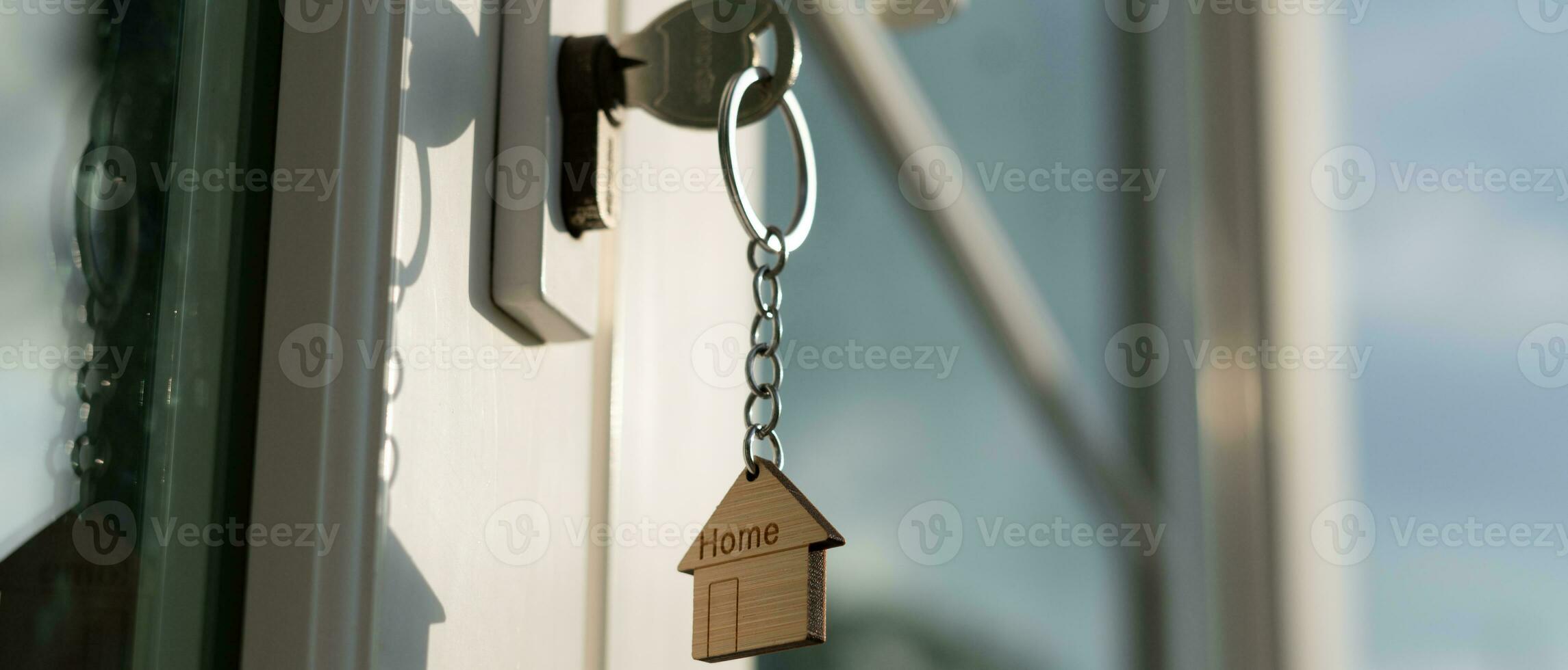 Landlord key for unlocking house is plugged into the door. Second hand house for rent and sale. keychain is blowing in the wind. mortgage for new home, buy, sell, renovate, investment, owner, estate photo