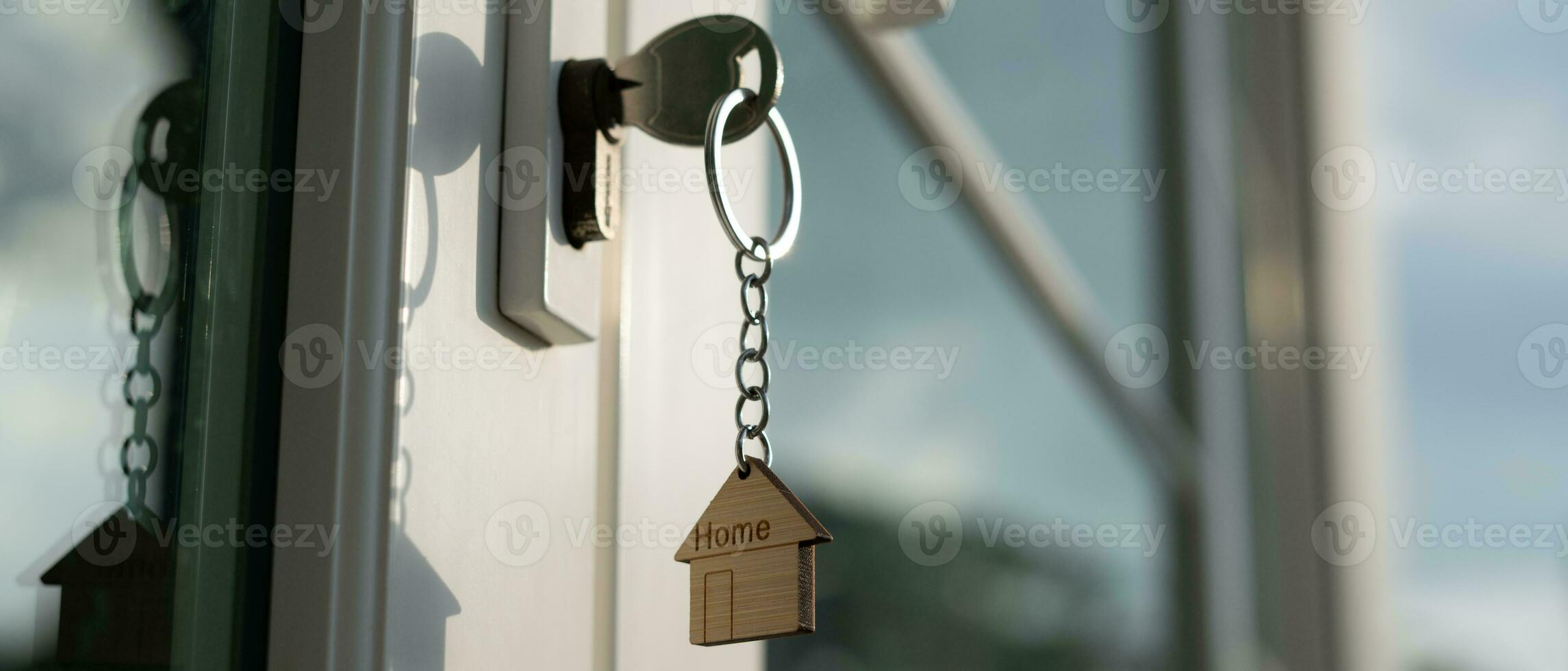 Landlord key for unlocking house is plugged into the door. Second hand house for rent and sale. keychain is blowing in the wind. mortgage for new home, buy, sell, renovate, investment, owner, estate photo