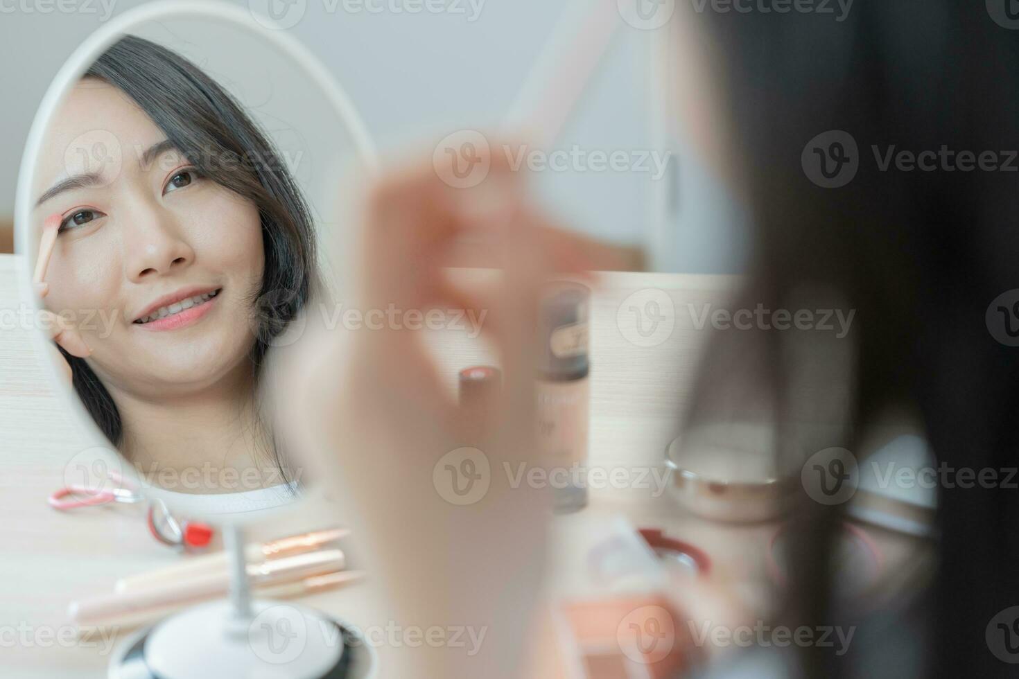 Beautiful Asian woman sit in front of a mirror. face of a healthy woman applying makeup. Advertisement for skin care, anti-wrinkle, baby face, whitening, moisturizer, tighten pores serum photo