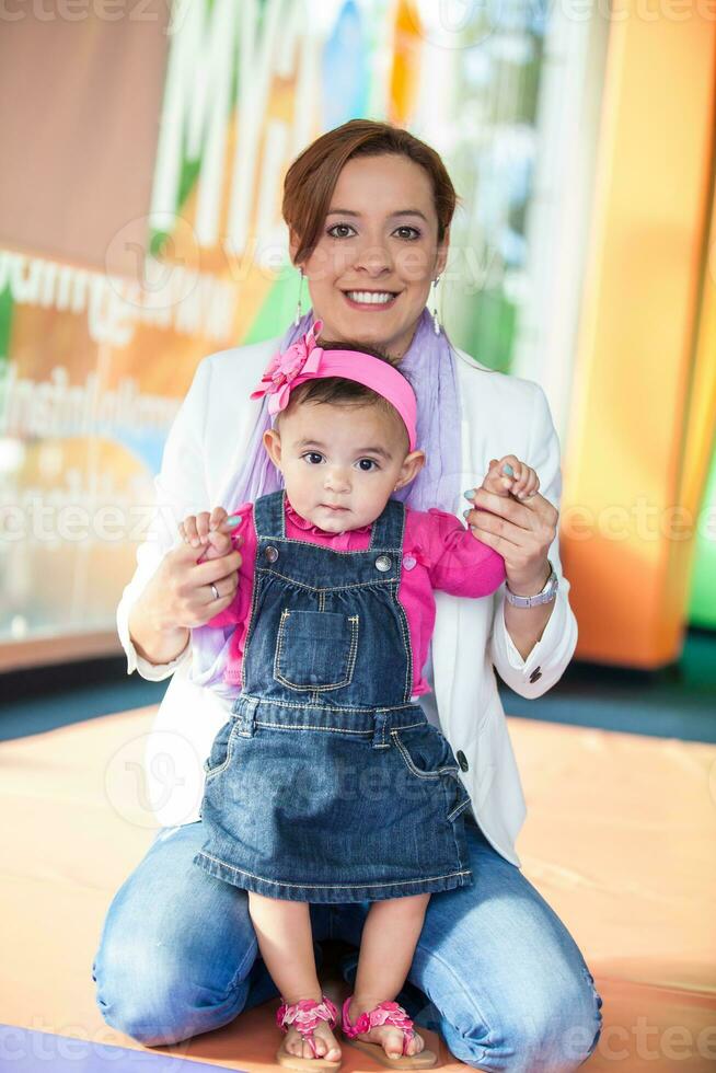 Young mother playing with her baby daughter. Early stimulation for toddlers concept. photo