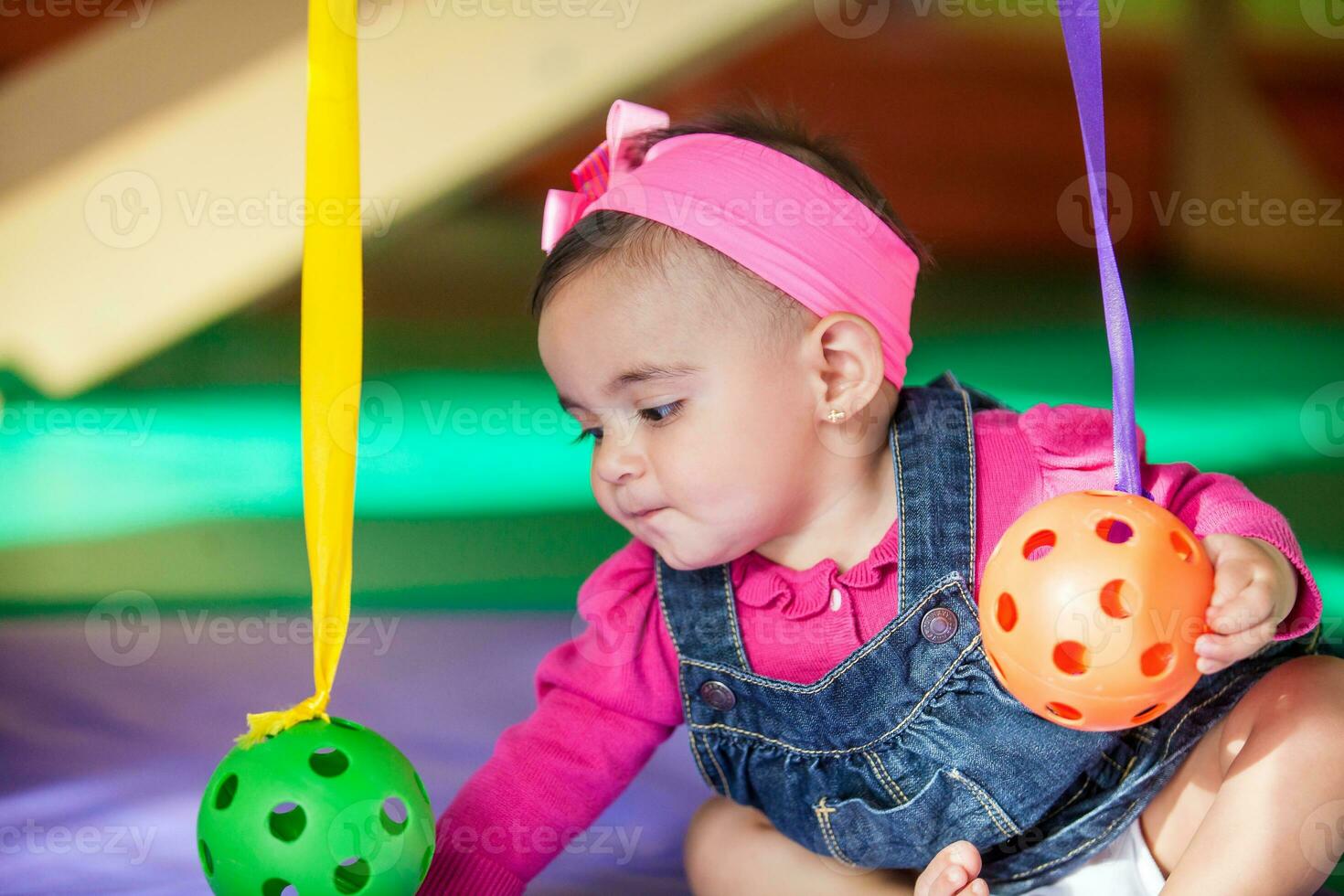 Beautiful ten months baby girl playing with colorful balls. Early stimulation for toddlers concept. photo