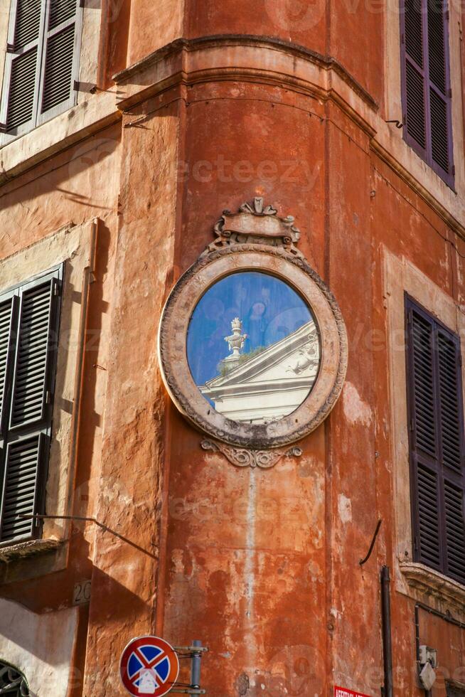 An small piece of the Santa Maria in Aquiro church reflected on a mirror at a corner of Piazza Capranica photo