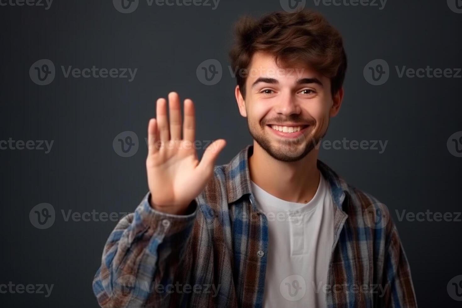 Portrait of a happy young man waving hand isolated over gray background photo