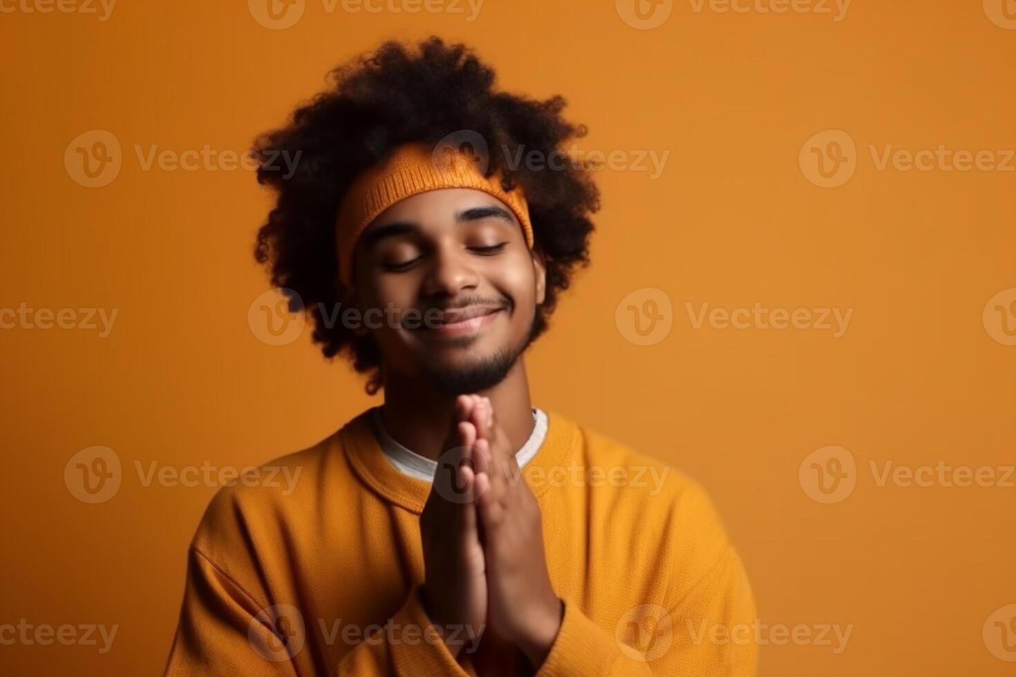 Portrait of a smiling young man praying over orange background photo