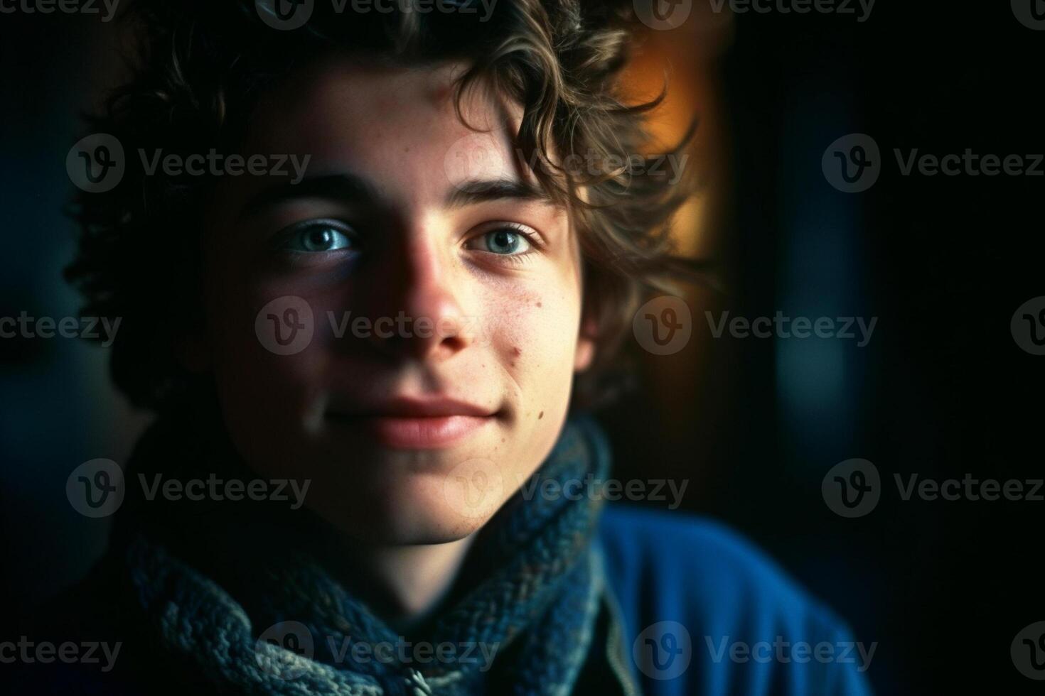 Portrait of a handsome young man with curly hair in a dark room photo