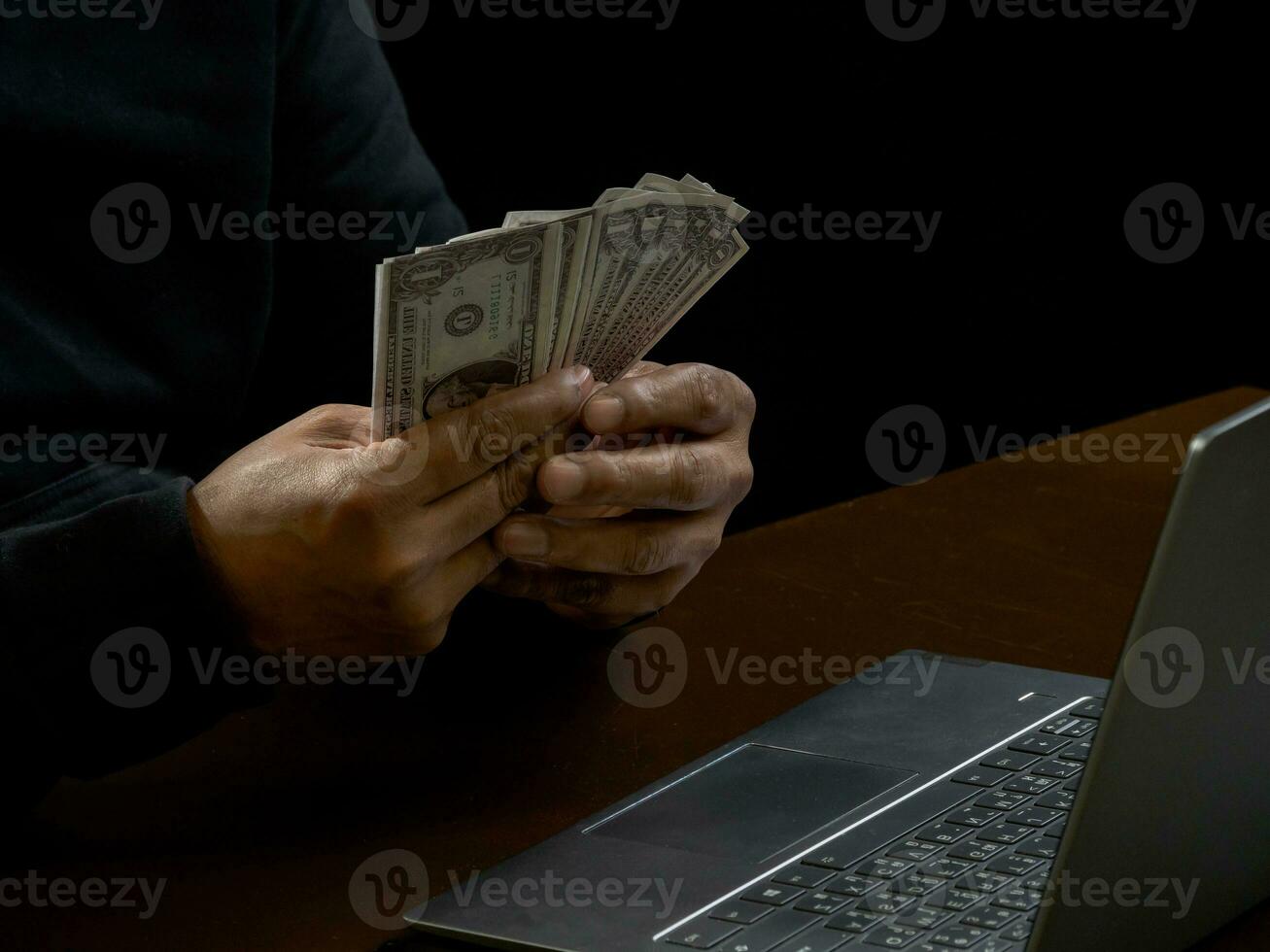 Hacker spy man one person in black hoodie sitting on a table looking computer laptop used login password attack security to circulate data digital in internet network system, night dark background. photo