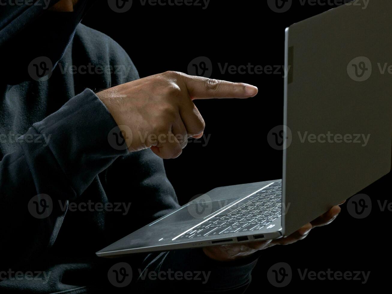 Hacker spy man one person in black hoodie sitting on a table looking computer laptop used login password attack security to circulate data digital in internet network system, night dark background. photo