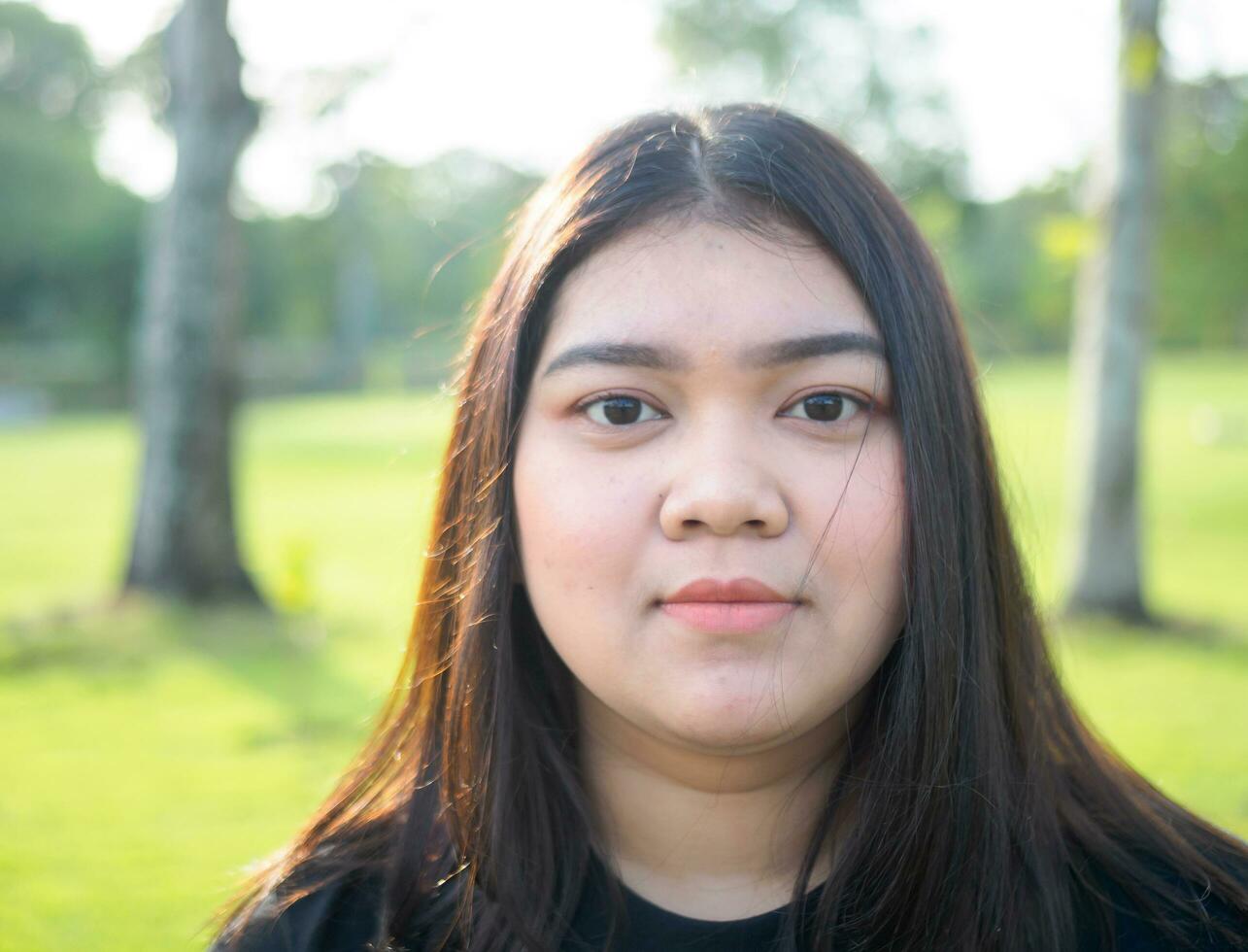 portrait young woman girl asian chubby cute beautiful long black hair one person wear black shirt looking  in garden park outdoor evening sunlight fresh smiling cheerful happy relax summer day photo