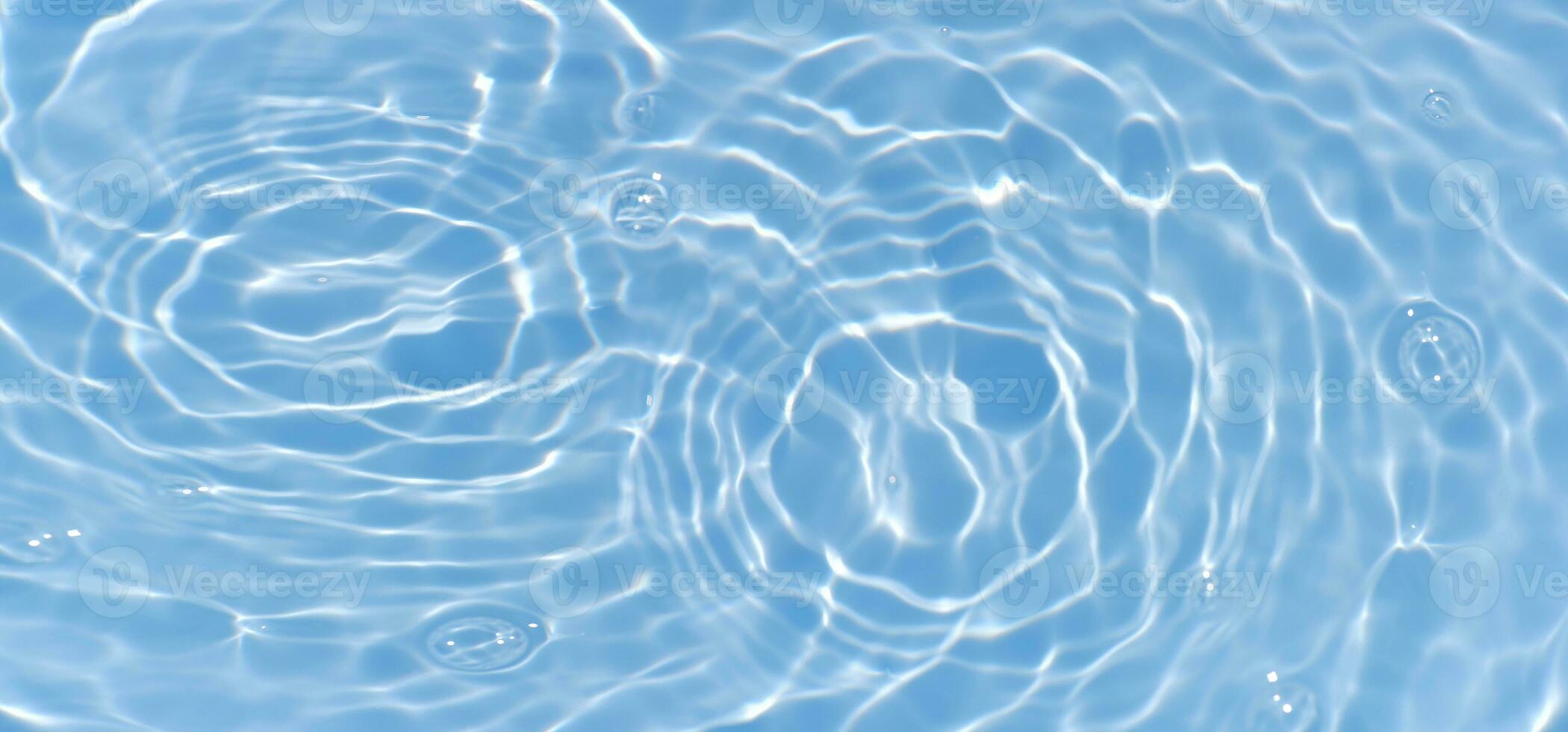 Blue water with ripples on the surface. Defocus blurred transparent blue colored clear calm water surface texture with splashes and bubbles. Water waves with shining pattern texture background. photo