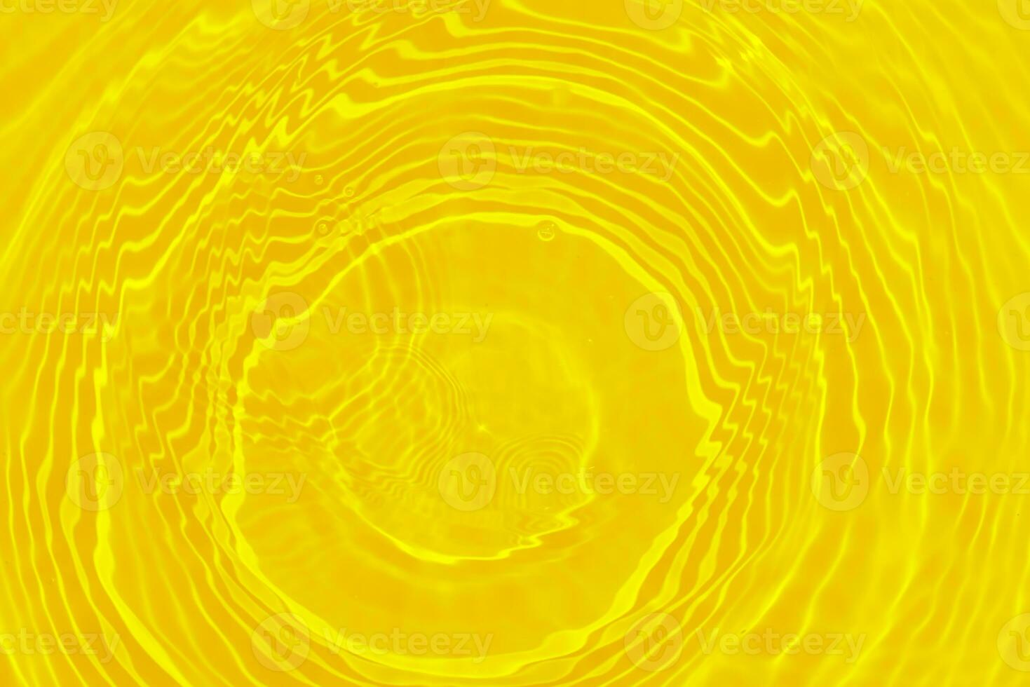 Yellow water with ripples on the surface. Defocus blurred transparent gold colored clear calm water surface texture with splashes and bubbles. Water waves with shining pattern texture background. photo