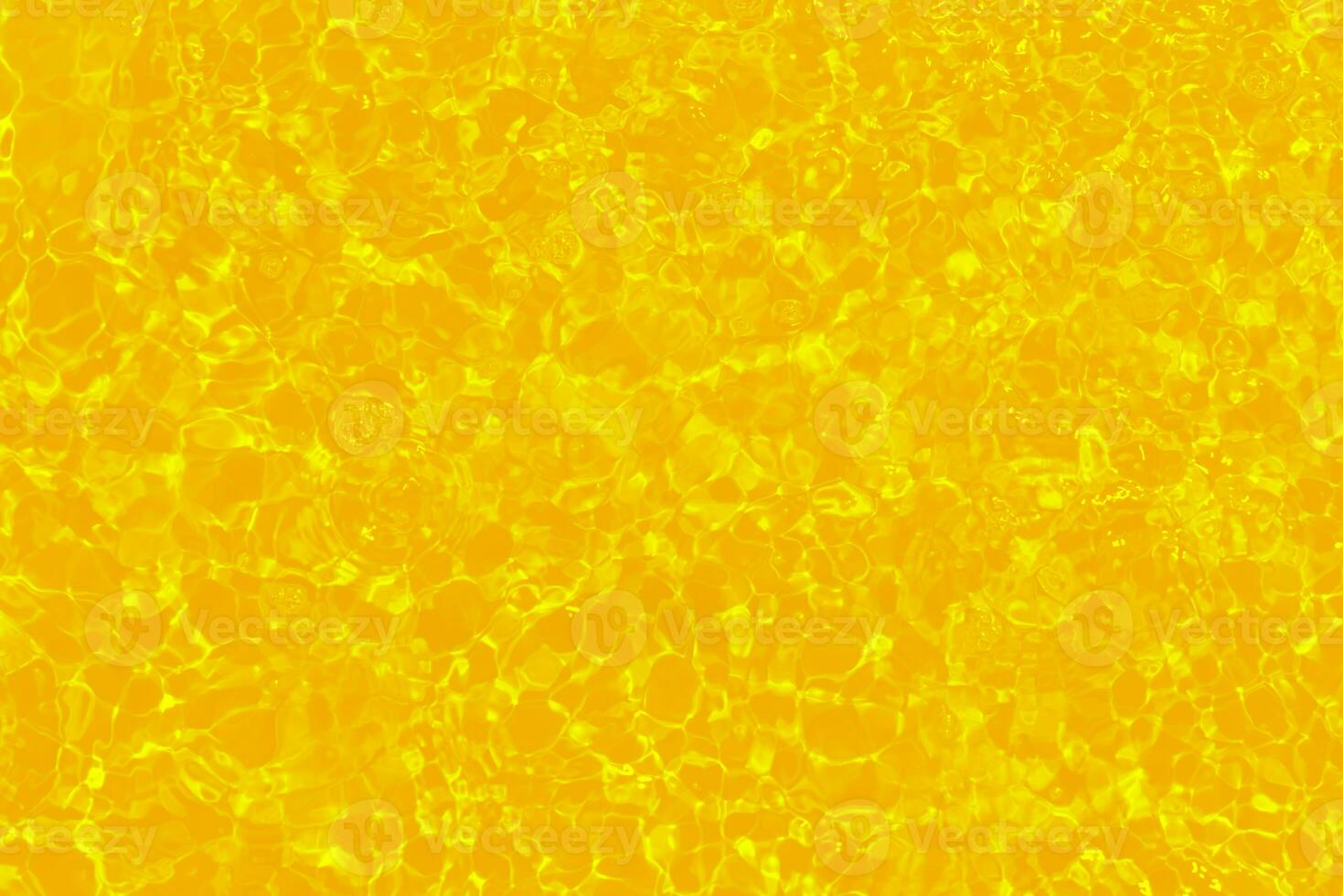 Yellow water with ripples on the surface. Defocus blurred transparent gold colored clear calm water surface texture with splashes and bubbles. Water waves with shining pattern texture background. photo