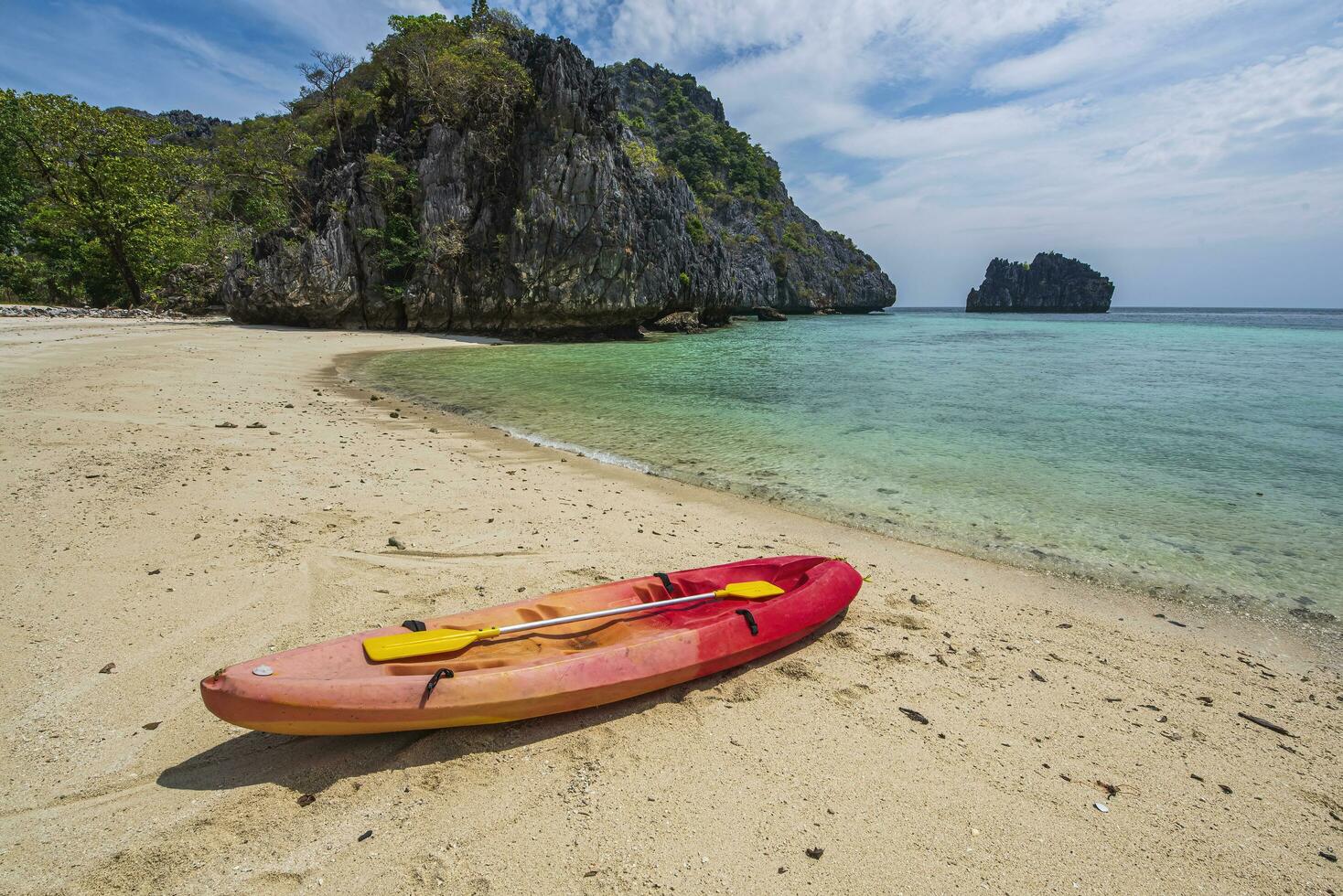 Beach on an island in Myanmar where there are no people There are 4 catak boats on the beach. The water is clear, emerald green, a bay with a small island in front of the bay. photo