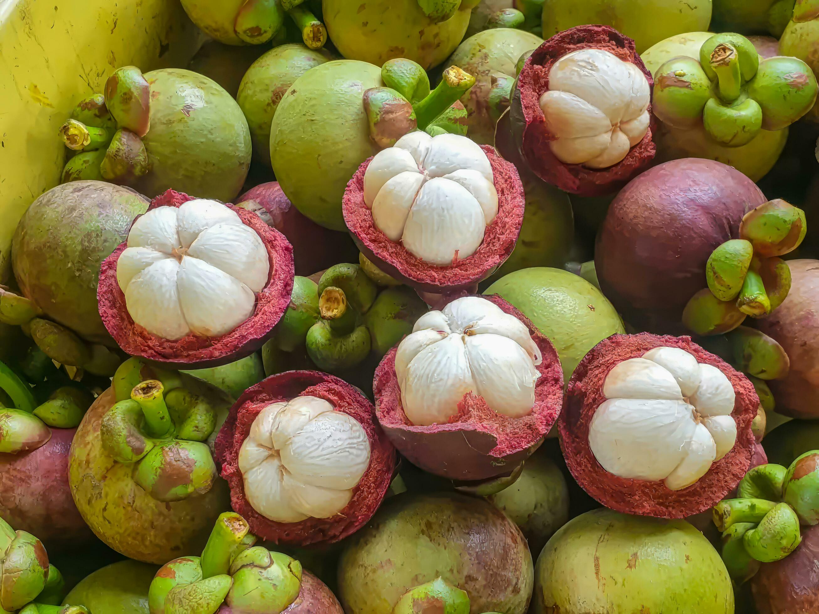 mangosteen in bulk. Half peeled mangosteen You can see the flesh of the