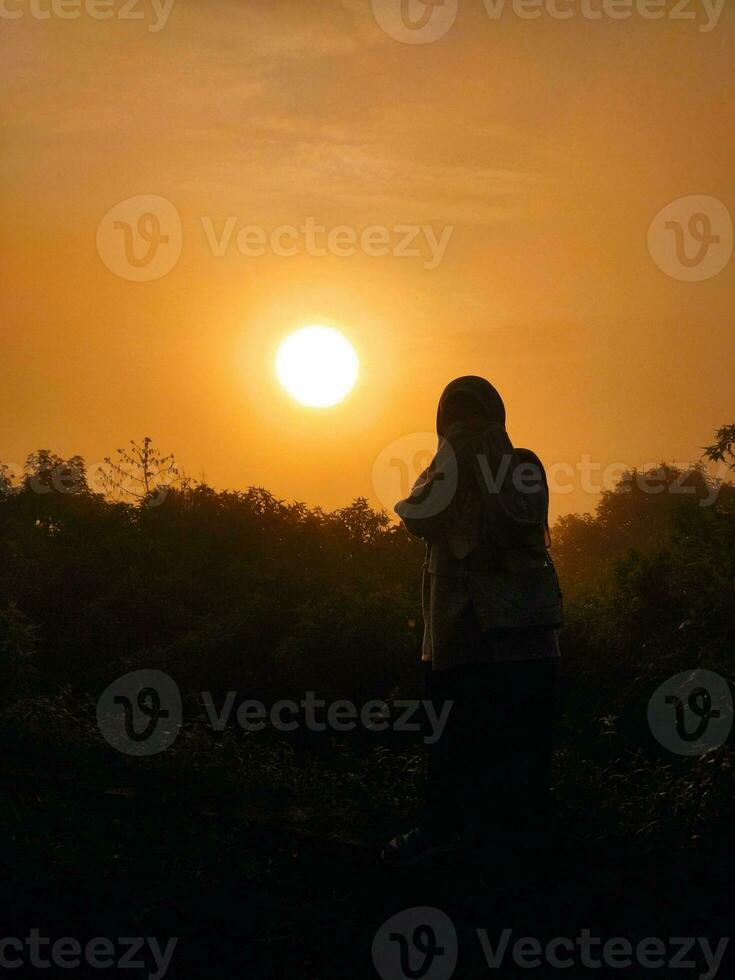 muslimah mujer en el puesta de sol foto