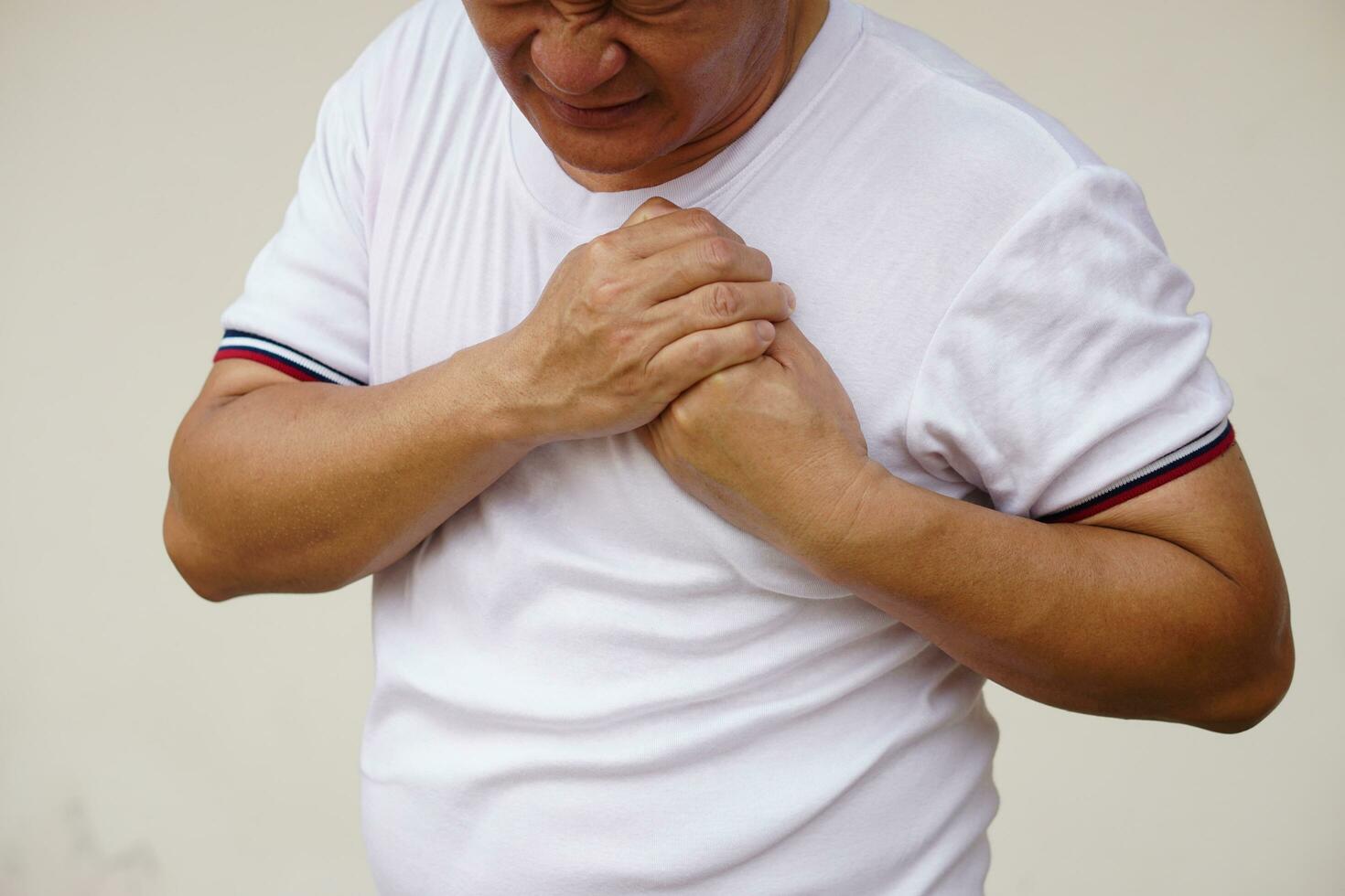 Closeup  Asian man  feels hurt his chest, suffering from chest pain. Concept, Heart attack , heart disease, stroke symptoms. Health problem. Sick and illness. photo