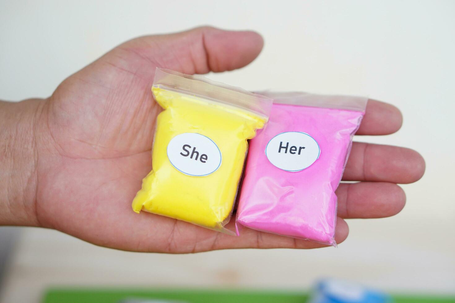 Close up hand holds  yellow bag with words She and pink bag with word Her. Concept, English  language grammar teaching materials. Subject pronoun and object pronoun. photo