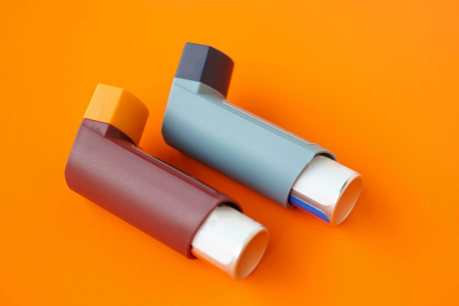 Asthma inhalers on orange background. Concept, Pharmaceutical products for treatment symptoms of asthma or COPD. Use under prescription. Health care device at home. photo