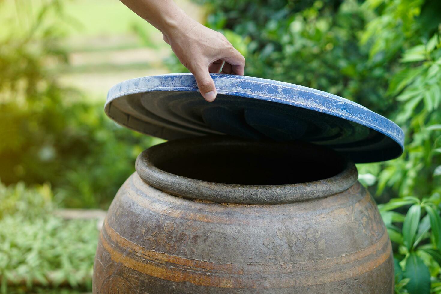 de cerca mano sostener tapa a cubrir agua tarro a proteger desde mosquito a raza dentro o otro insectos o polvo Vamos dentro agua. concepto, Campaña a detener mosquitos ciclo a laico huevos en agua envase foto