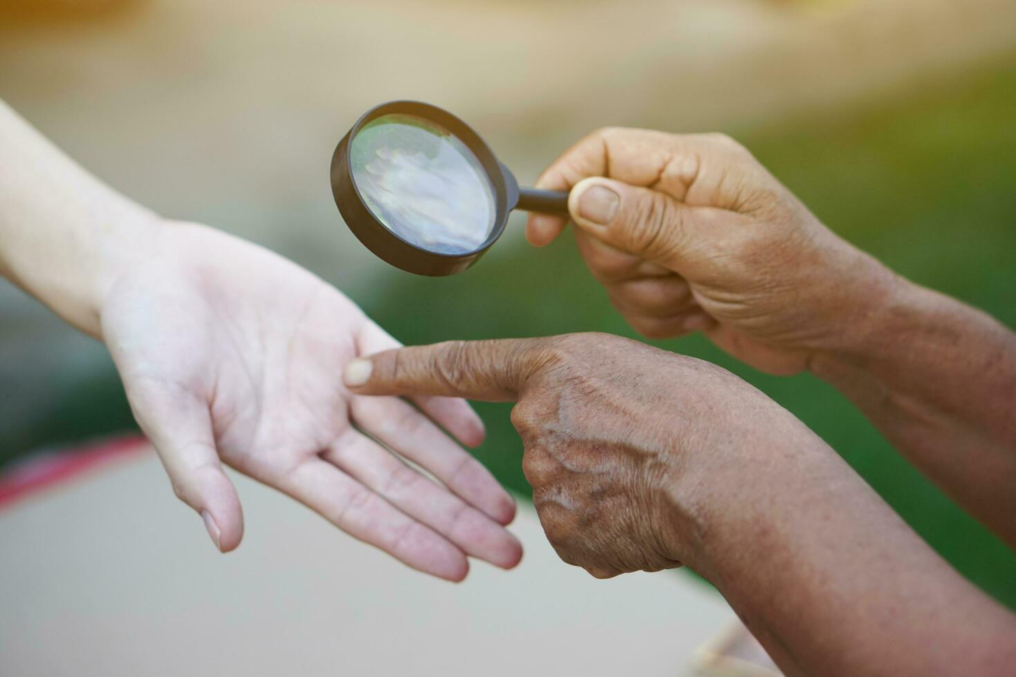 Closeup hand holds magnifying glass to inspect palm lines. Concept , palmistry, astrology. Foretelling, mystery, magic, fortune, fate. Prediction for future life , events.  Palmist predicting. photo