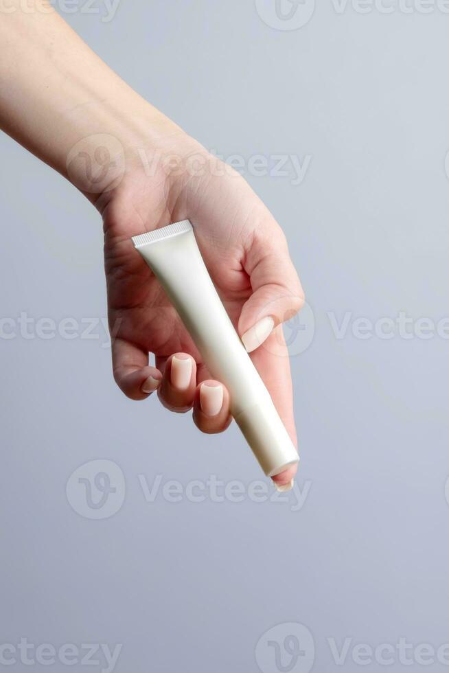 Woman hand showing eye cream product. Cosmetic product branding mockup. Daily skincare and body care routine. Female hand holding cosmetic product mockup, close up. photo