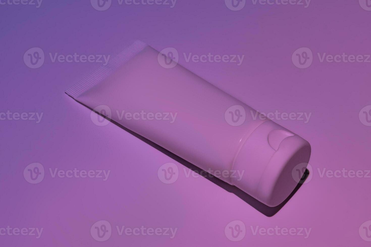 Unbranded white squeeze cosmetic cream bottle tube on neon pink background. Natural oranic spa cosmetics concept. Mockup, template photo