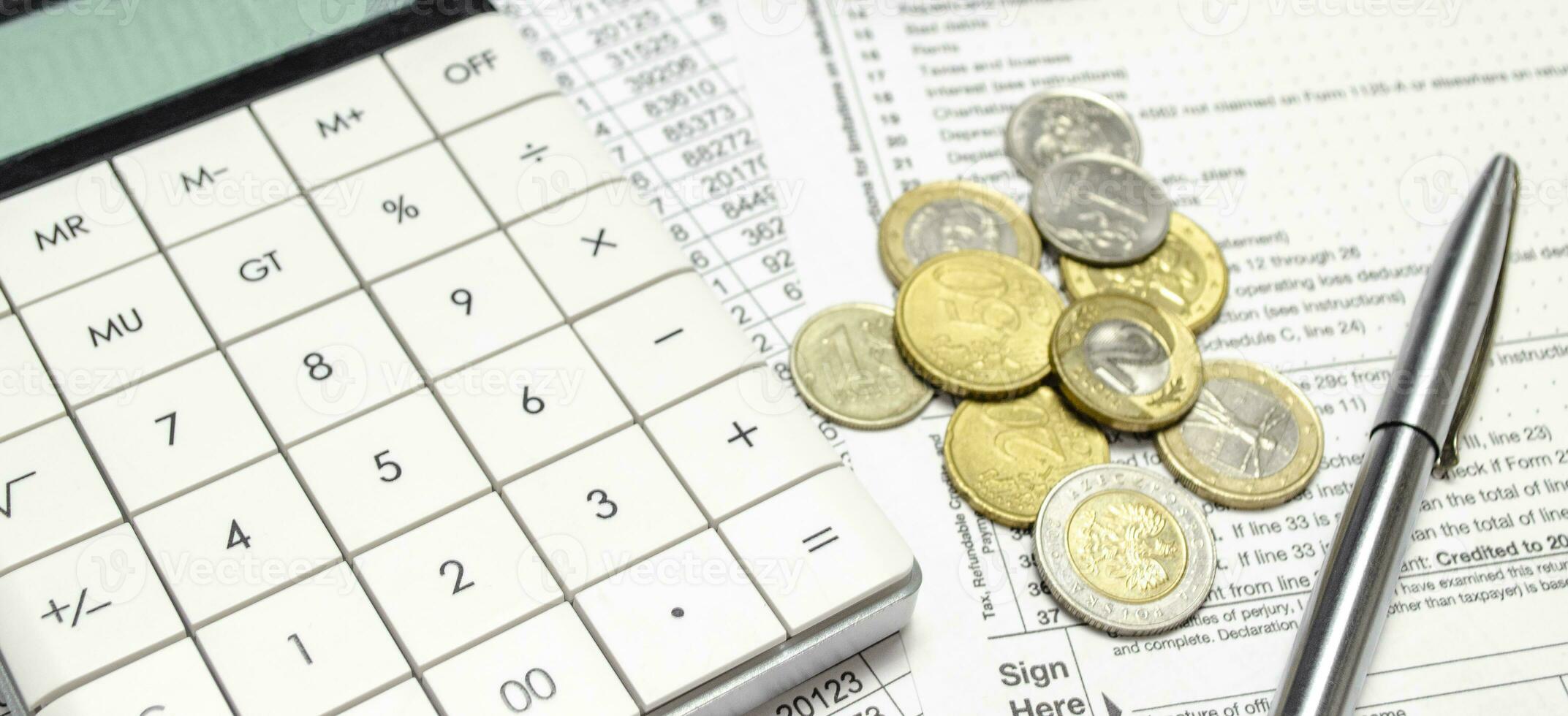 calculator with stack of coins and pen on papers photo