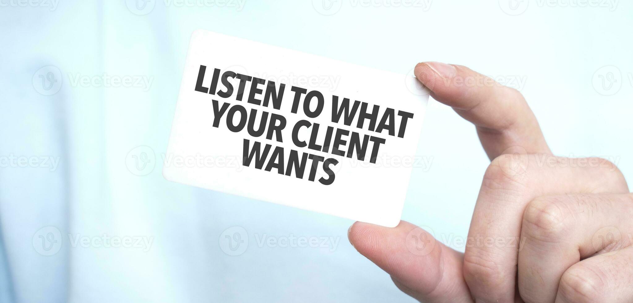 hombre en azul camisa de entrenamiento participación un tarjeta con texto escucha a qué tu cliente quiere, negocio concepto foto