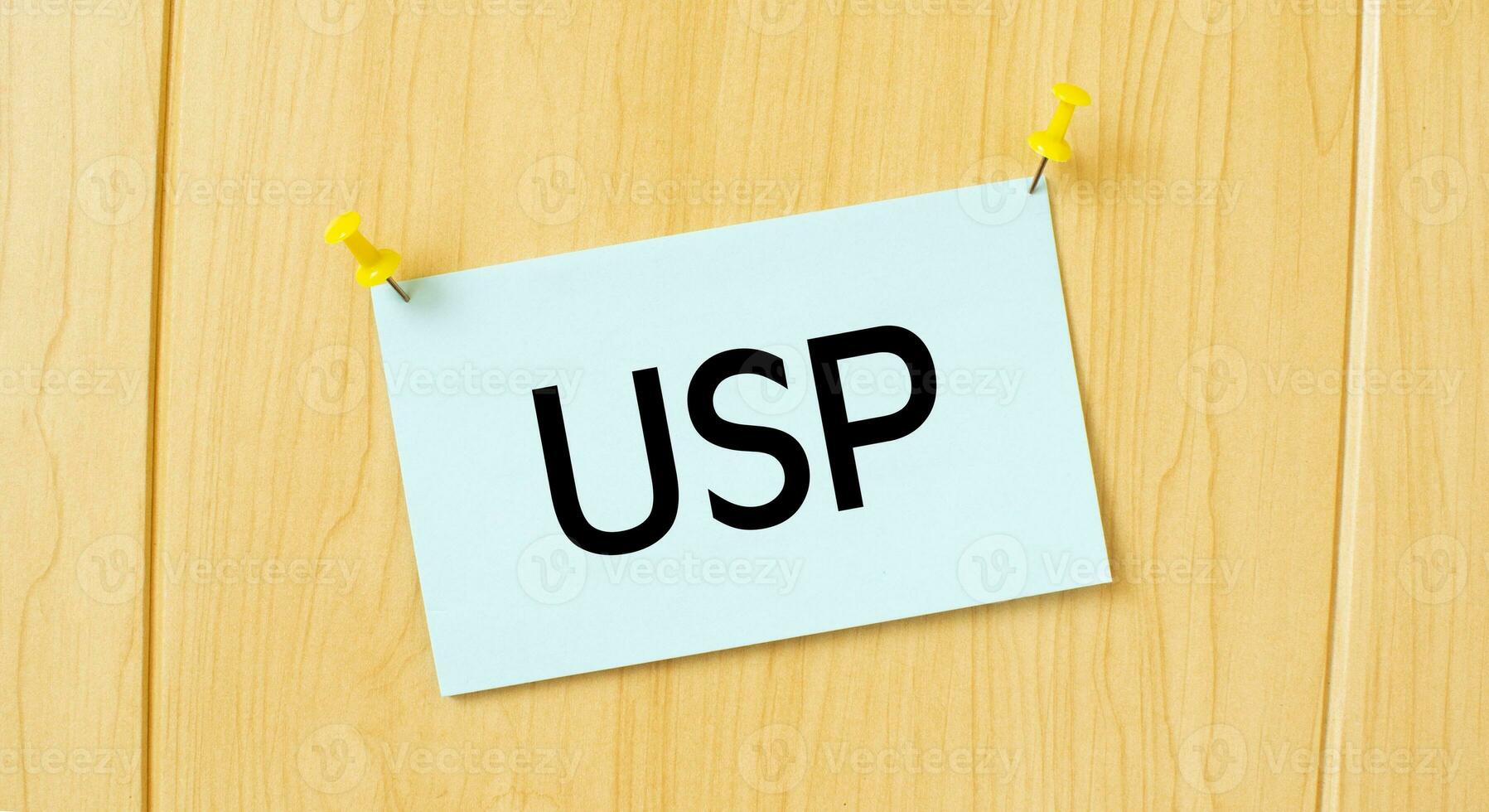 USP sign written on sticky note pinned on wooden wall photo