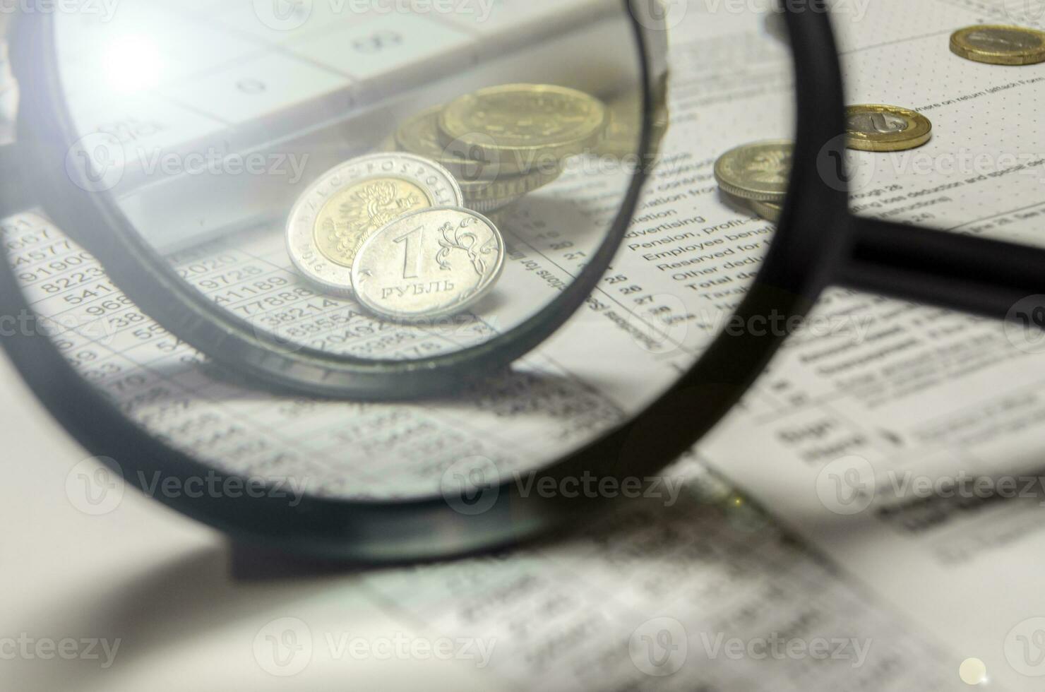 A magnifying glass with coins in the background isolated on an empty white background photo