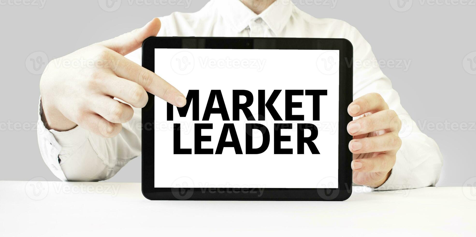 Text MARKET LEADER on tablet display in businessman hands on the white background. Business concept photo