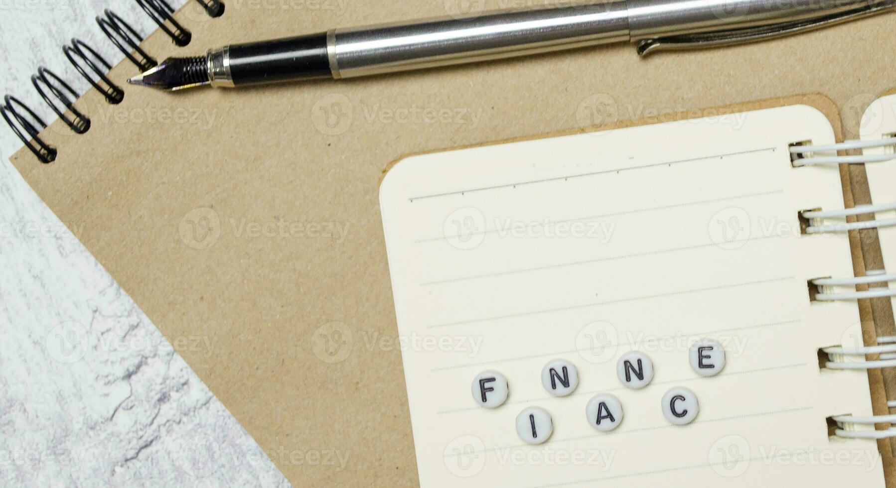 Word FINANCE with pen and notebooks on white wooden background photo