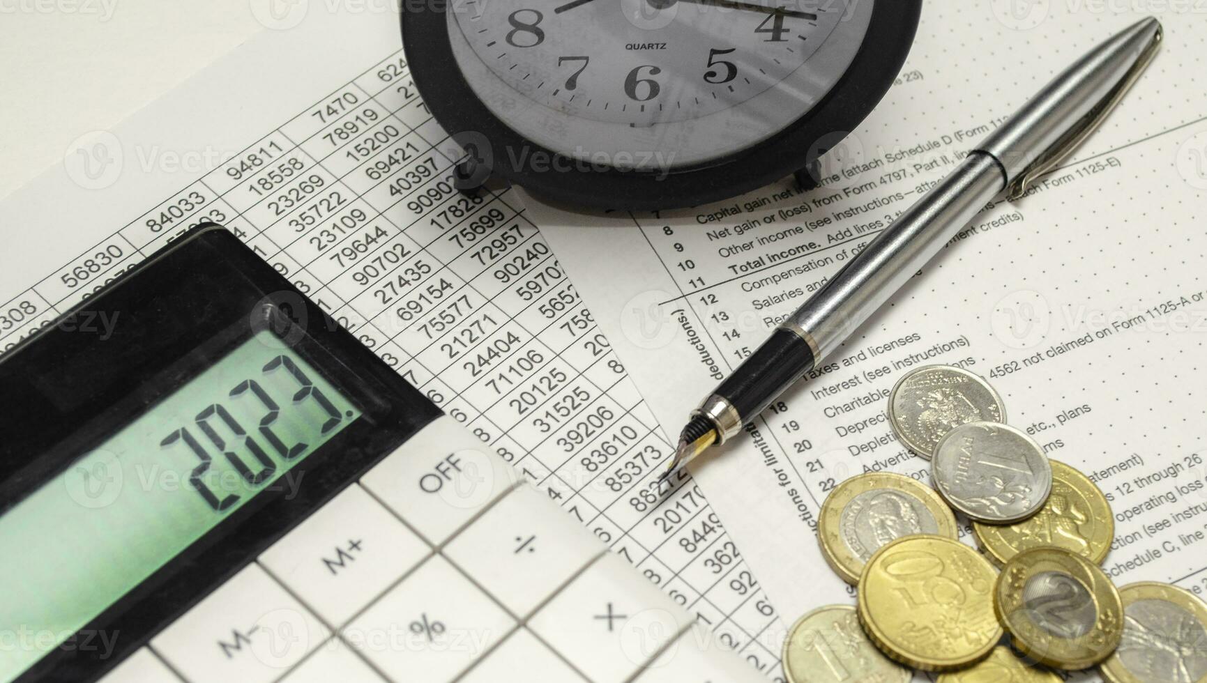Word 2023 on calculator display with alarm clock, coins and pen photo