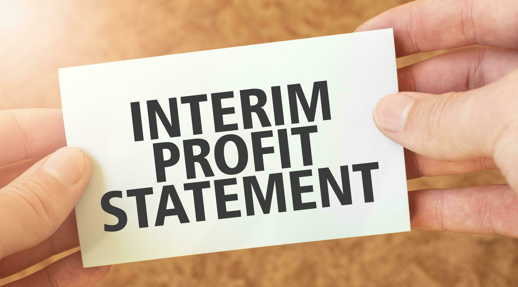 INTERIM PROFIT STATEMENT word inscription on white card paper sheet in hands of a businessman. recap concept. red and white paper photo
