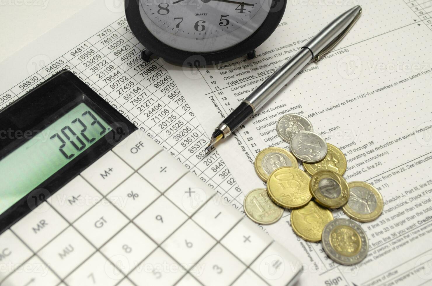 Word 2023 on calculator display with alarm clock, coins and pen photo