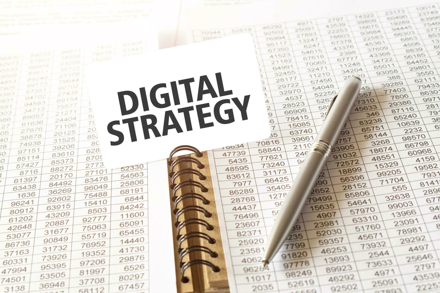 Text DIGITAL STRATEGY on paper card, pen, financial documentation on table photo